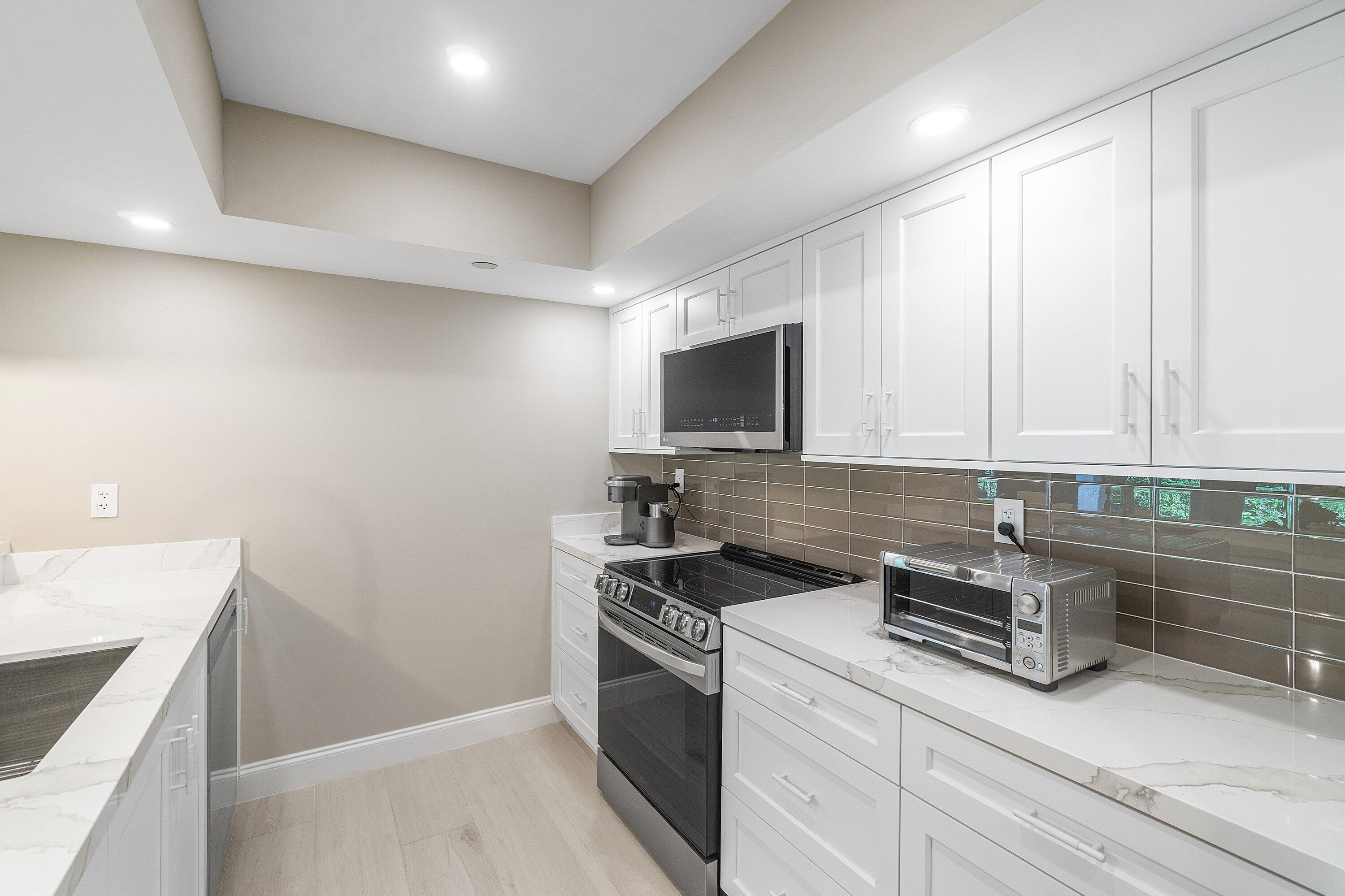 100 Southeast 5th Avenue, Unit 404 Boca Raton, FL 33432 - Photo 15 of 46 a kitchen with stainless steel appliances white cabinets and a stove top oven