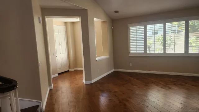 a view of an empty room with wooden floor fireplace and a window