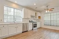 a large kitchen with granite countertop a stove a sink a window and dining table