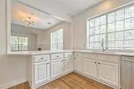 a kitchen with white cabinets and a large window