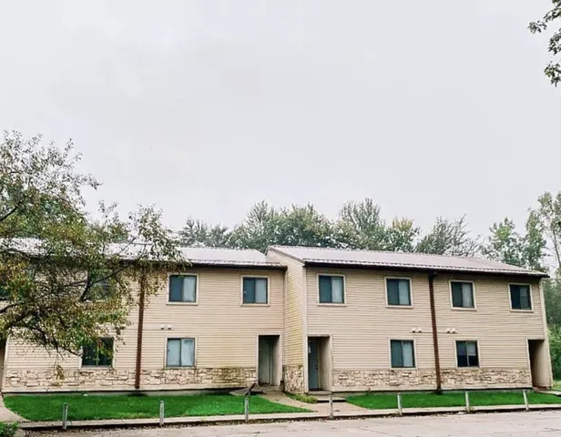 a white house with a small yard and large trees