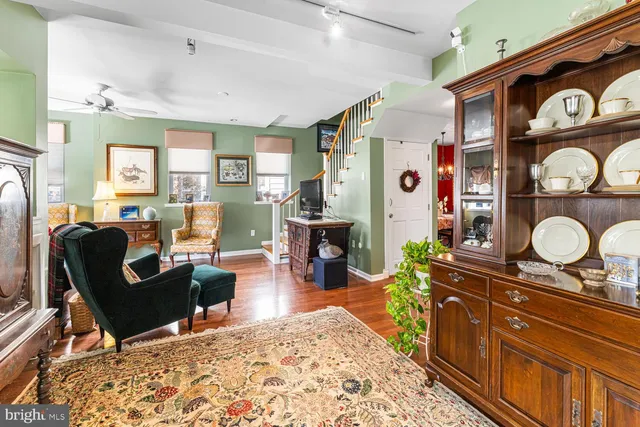 a living room with furniture a computer on a desk and bookshelf with wooden floor