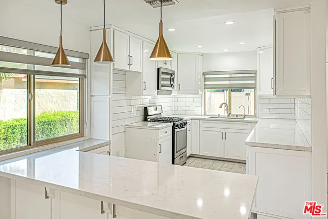 a kitchen filled with white cabinets and white appliances
