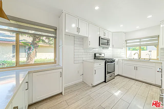 a kitchen with white cabinets a sink a window and stainless steel appliances