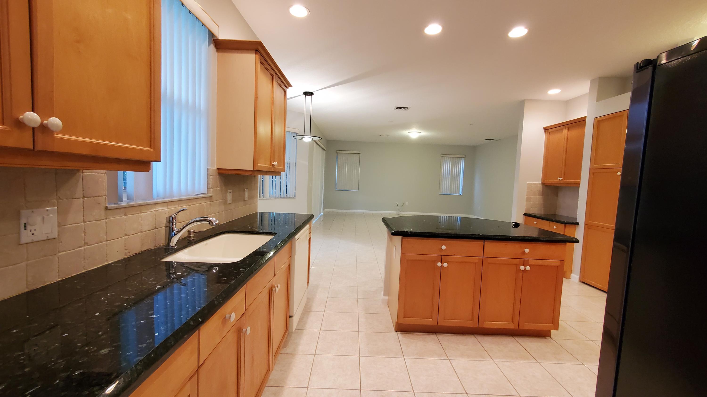 2252 Ridgewood Circle Royal Palm Beach, FL 33411 - Photo 4 of 40 a kitchen with stainless steel appliances granite countertop a sink and a refrigerator