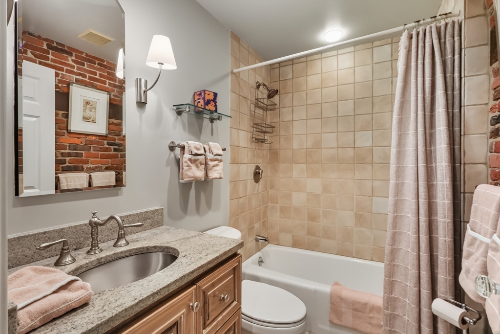 130 Fulton Street, Unit 7 Boston, MA 02109 - Photo 18 of 24 a bathroom with a granite countertop sink toilet and shower