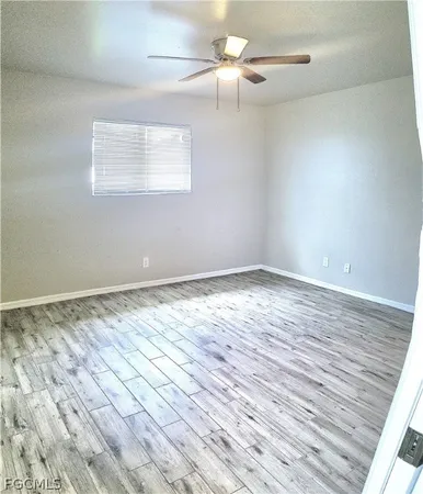 an empty room with wooden floor fan and windows