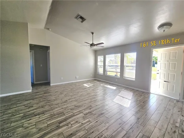 a view of an empty room with wooden floor and a window