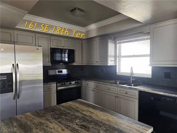 a kitchen with stainless steel appliances granite countertop a sink a stove a refrigerator and a microwave