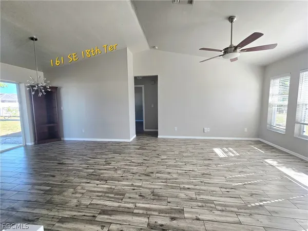 a view of empty room with window and wooden floor