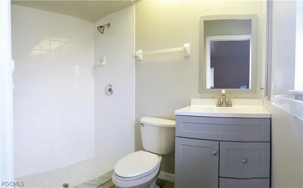 a bathroom with a granite countertop toilet a sink and a mirror