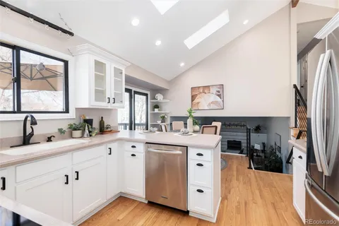 a kitchen with stainless steel appliances a sink a stove a refrigerator cabinets and a dining table