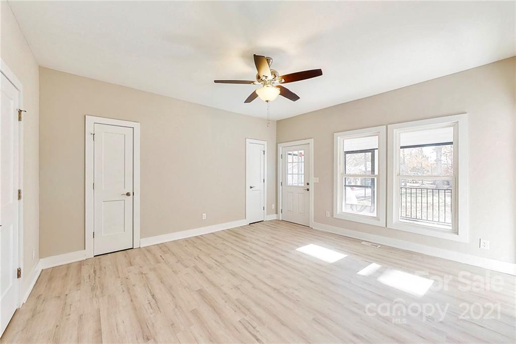 313 Old Williams Road Wingate, NC 28174 - Photo 22 of 46 an empty room with wooden floor ceiling fan and windows