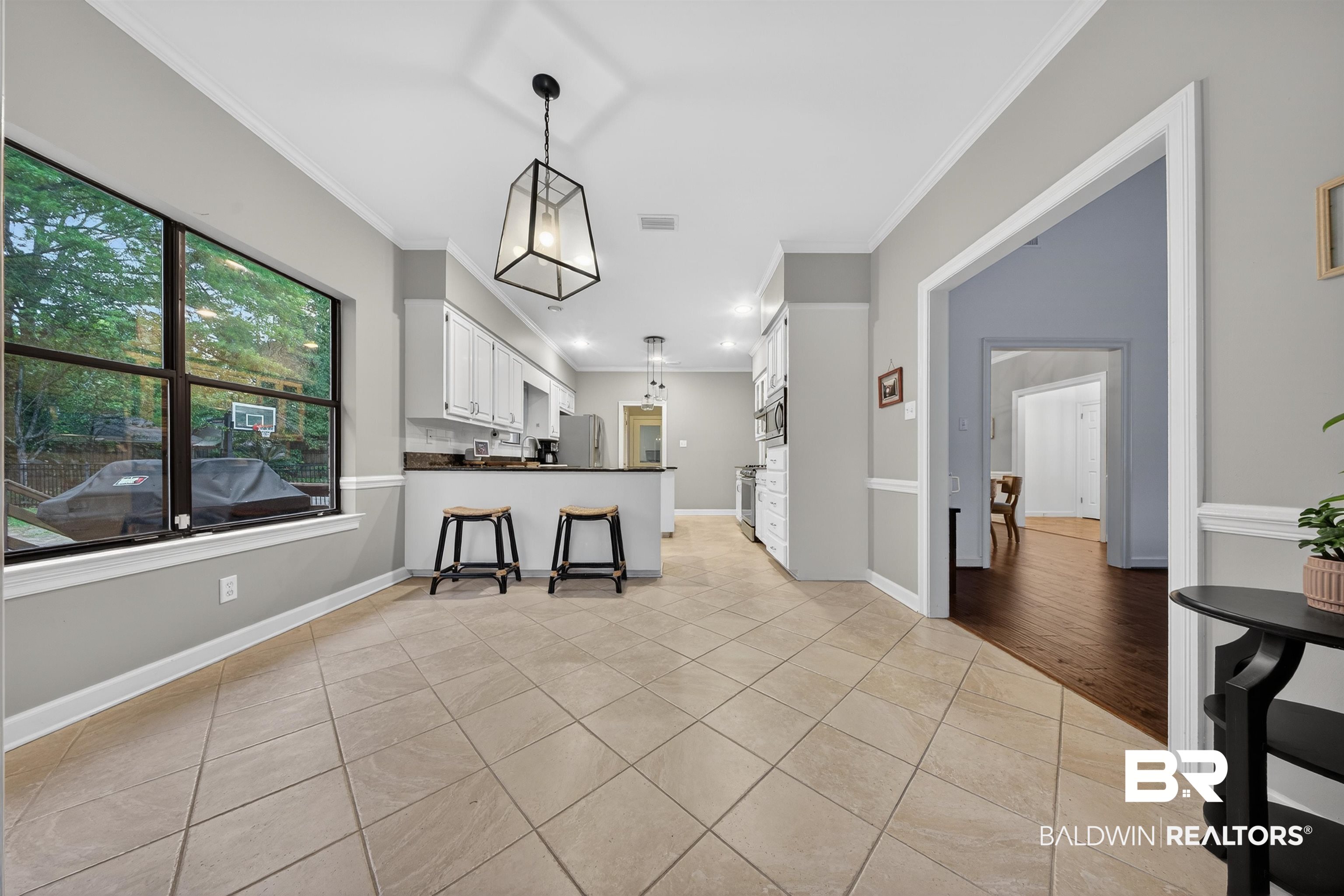 1250 Savannah Drive Mobile, AL 36609 - Photo 13 of 35 Kitchen featuring white cabinetry, light tile patterned flooring, a kitchen bar, dark countertops, and crown molding