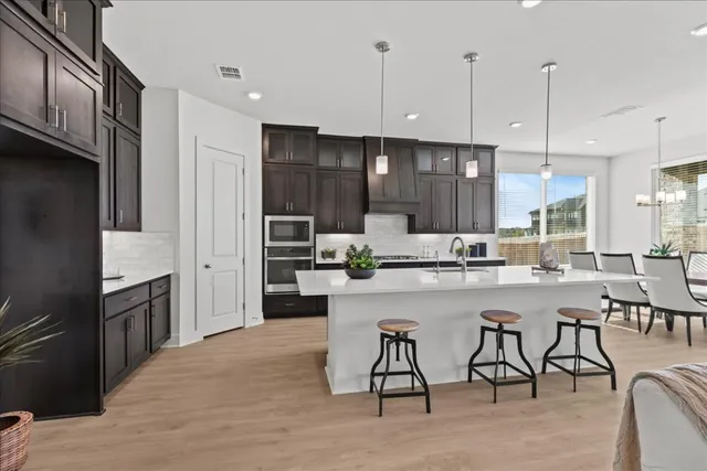 a kitchen with stainless steel appliances kitchen island granite countertop a table chairs sink and cabinets