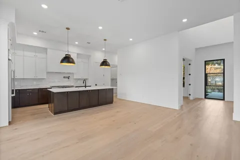 a kitchen with kitchen island stainless steel appliances a sink a stove and a wooden floors