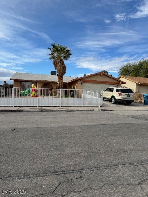Single story home with a fenced front yard, a garage, and driveway