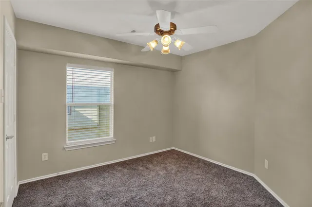 an empty room with a chandelier fan and window