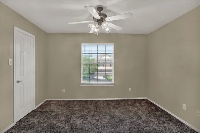 an empty room with a chandelier fan and windows
