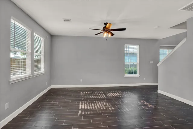 a view of empty room with wooden floor and fan