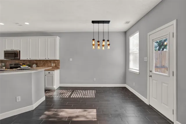 a view of kitchen with a sink wooden cabinets and chandelier