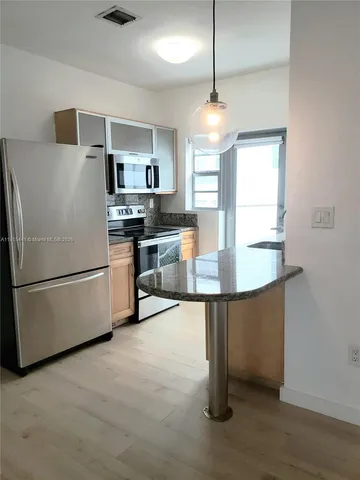 a kitchen with stainless steel appliances granite countertop a refrigerator a sink a stove and a microwave