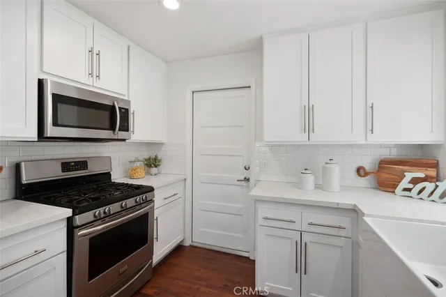 a kitchen with cabinets stainless steel appliances and a wooden floor