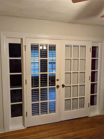 a view of an empty room with wooden floor and windows