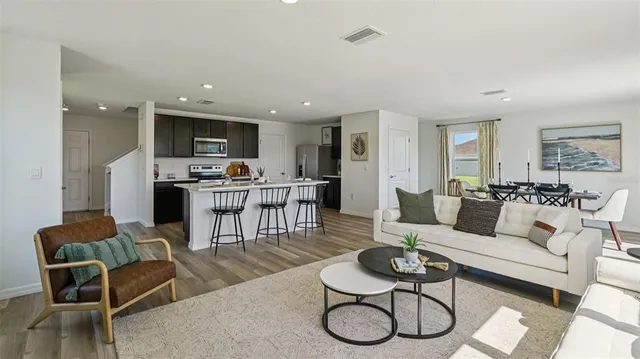 a living room with furniture a rug kitchen view and a window
