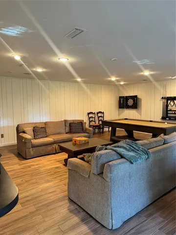 a living room with furniture kitchen view and a wooden floor