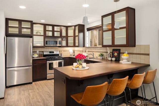 a kitchen with stainless steel appliances granite countertop a dining table chairs and a refrigerator