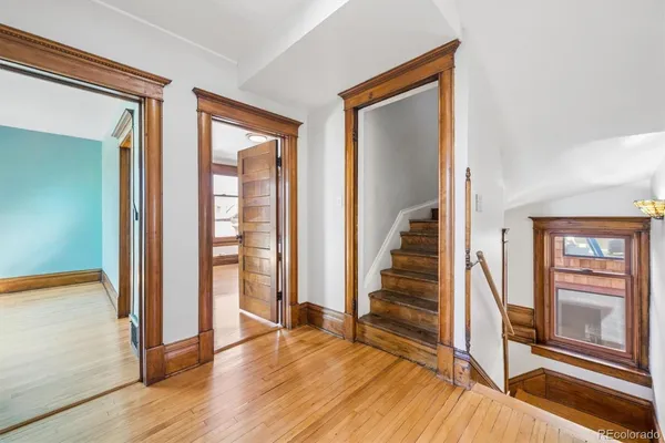a view of a hallway with wooden floor and staircase