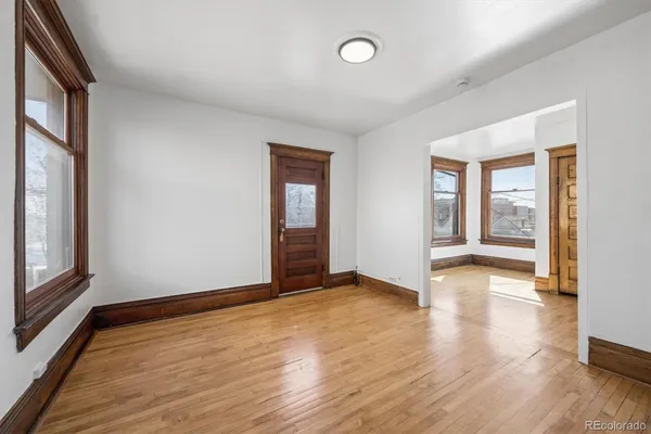 an empty room with wooden floor and windows