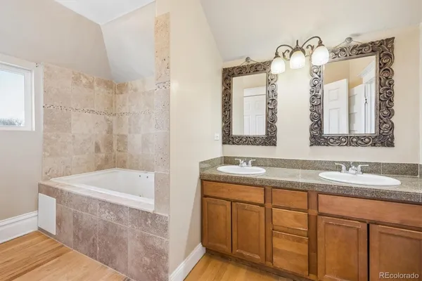 a bathroom with a double vanity sink mirror and bathtub
