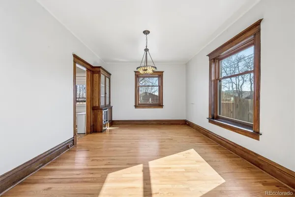 a view of an empty room with window and wooden floor