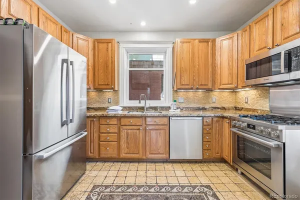 a kitchen with stainless steel appliances granite countertop a refrigerator a stove and a sink