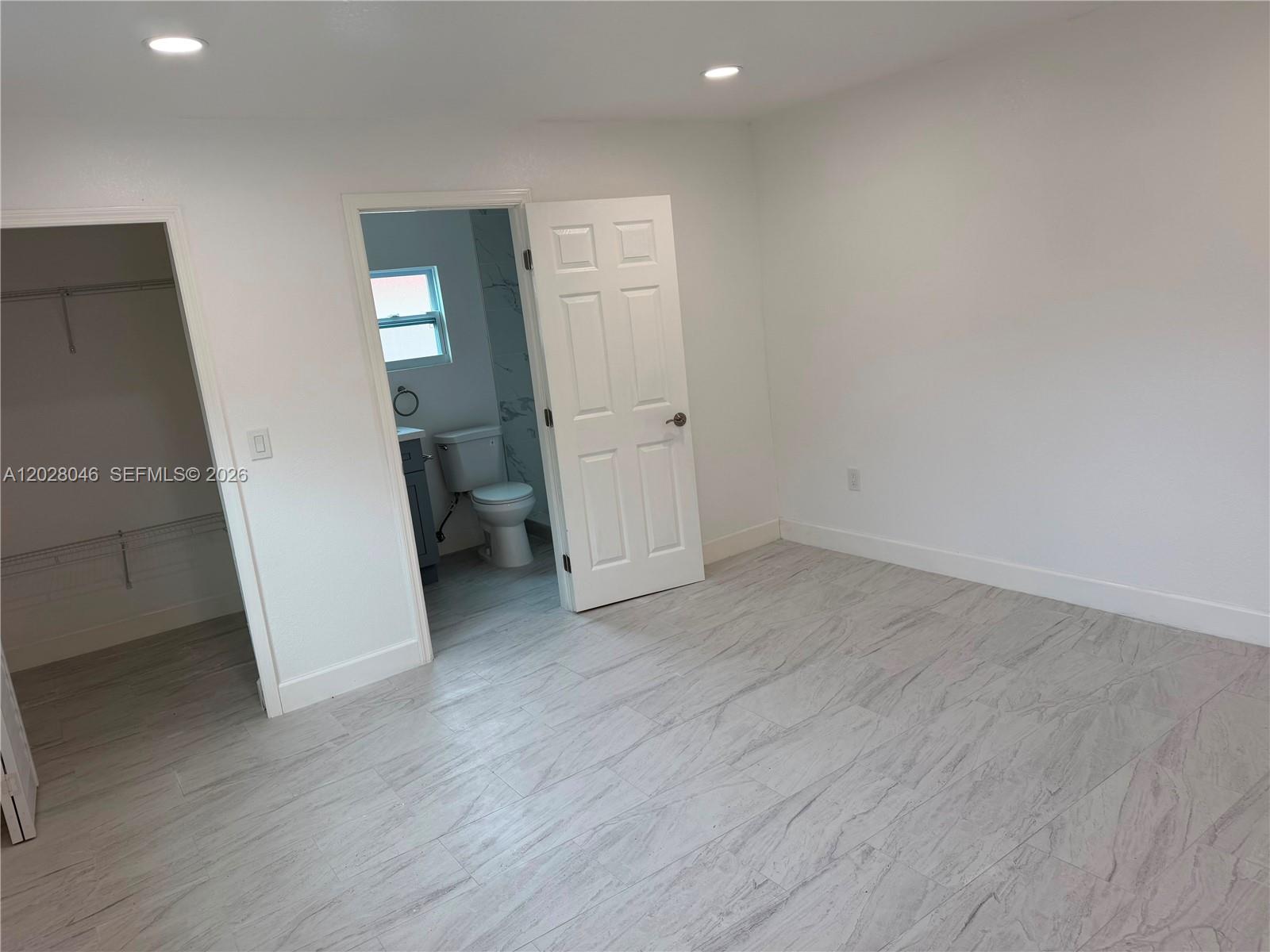 19321 Southwest 196th Street, Unit 1 Miami, FL 33187 - Photo 6 of 10 an empty room with wooden floor and white doors