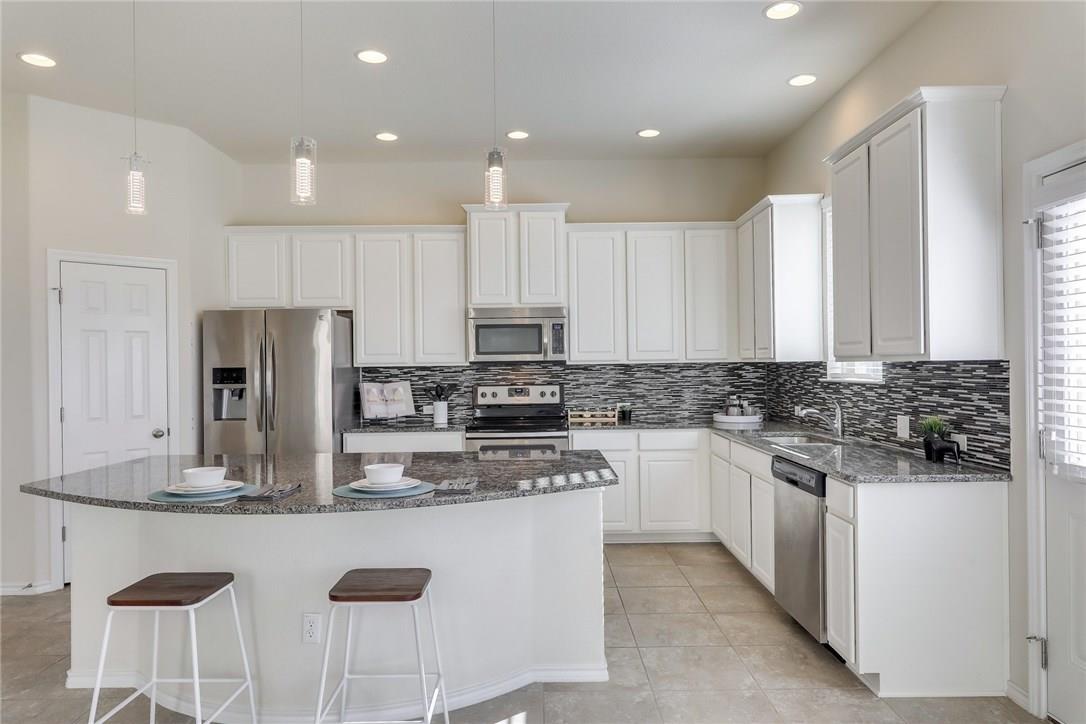 2105 Town Centre Drive, Unit 49 Round Rock, TX 78664 - Photo 4 of 22 a kitchen with stainless steel appliances granite countertop a stove top oven a refrigerator a sink and white cabinets