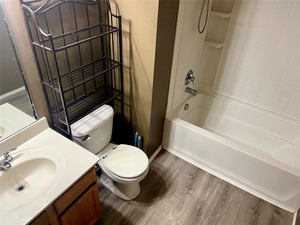 2533 Grand Gulf Road Fort Worth, TX 76123 - Photo 11 of 13 Full bathroom featuring a textured wall, washtub / shower combination, dark wood-type flooring, and vanity