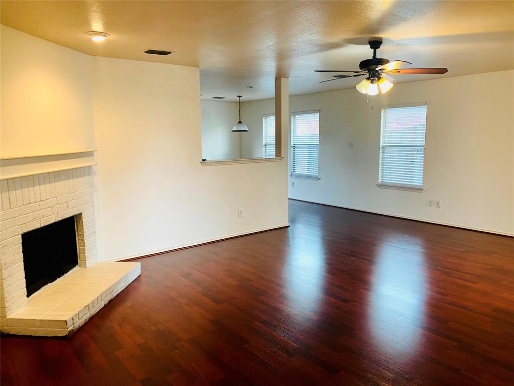 2533 Grand Gulf Road Fort Worth, TX 76123 - Photo 3 of 13 Unfurnished living room with a fireplace, dark wood-style floors, ceiling fan, and a textured ceiling