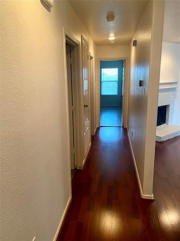 2533 Grand Gulf Road Fort Worth, TX 76123 - Photo 6 of 13 Hallway featuring a textured wall and dark wood-style flooring