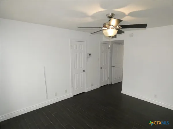 an empty room with wooden floor fan and window