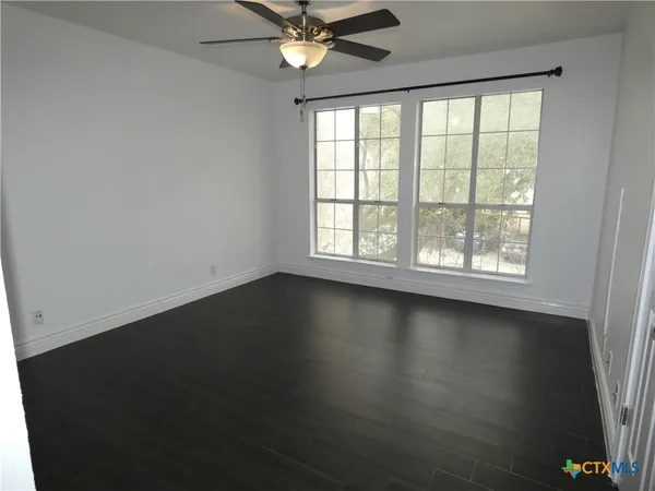 an empty room with wooden floor and windows