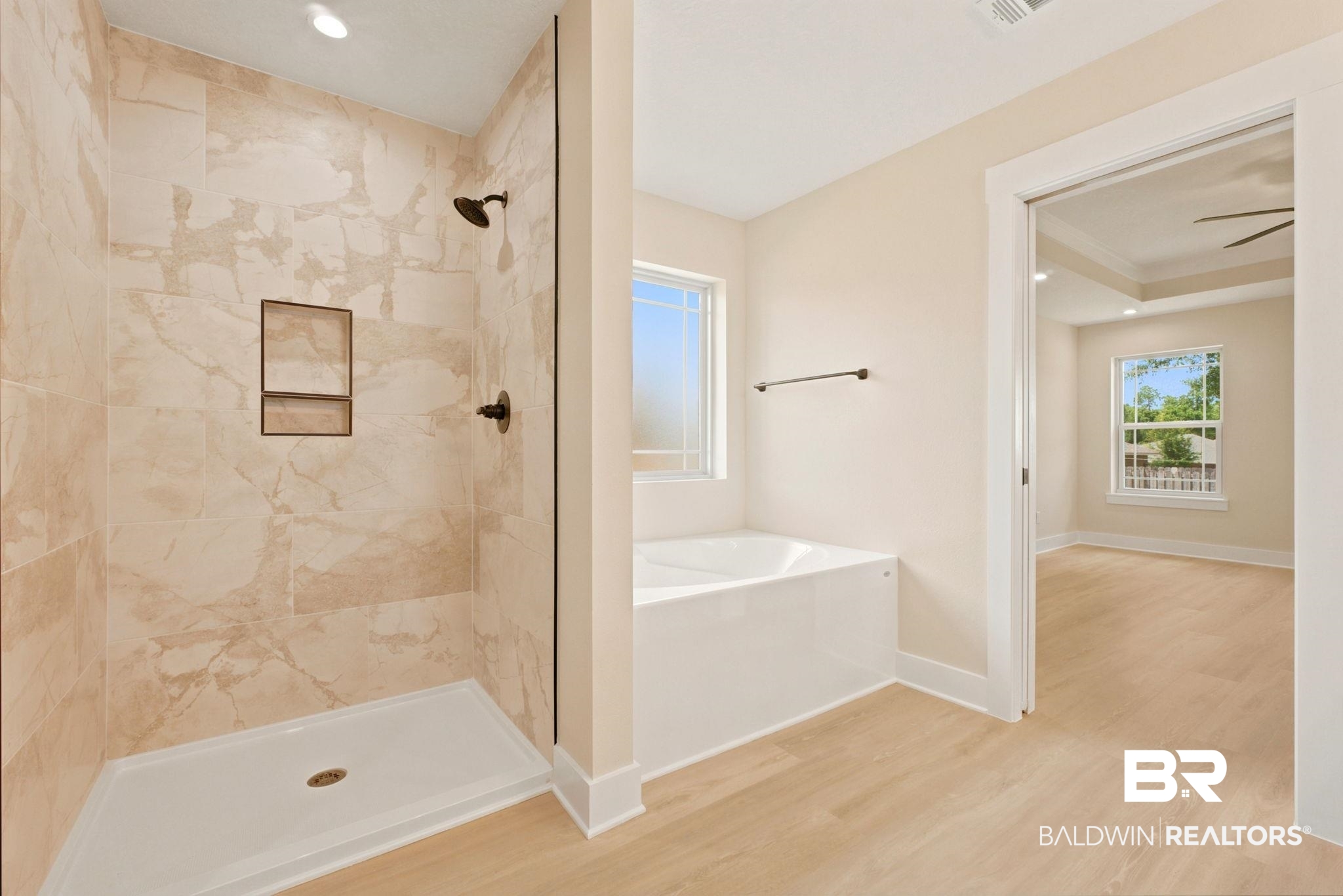 32656 Arbor Ridge Circle Lillian, AL 36549 - Photo 19 of 56 Spacious bathroom featuring a tiled walk-in shower with built-in niche, separate soaking tub beneath a window, and light wood-finish flooring