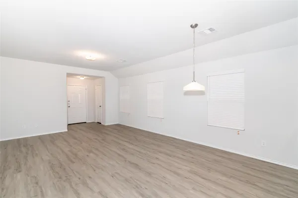 a view of an empty room with wooden floor and windows