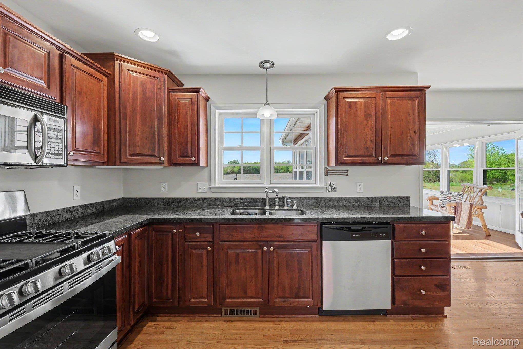 6520 Cook Road Swartz Creek, MI 48473 - Photo 17 of 43 Kitchen with stainless steel appliances, decorative light fixtures, light wood-style floors, and dark stone counters