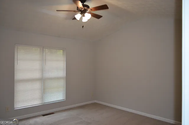 an empty room with windows and fan
