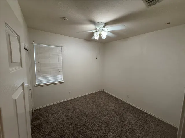 an empty room with a fan & a window