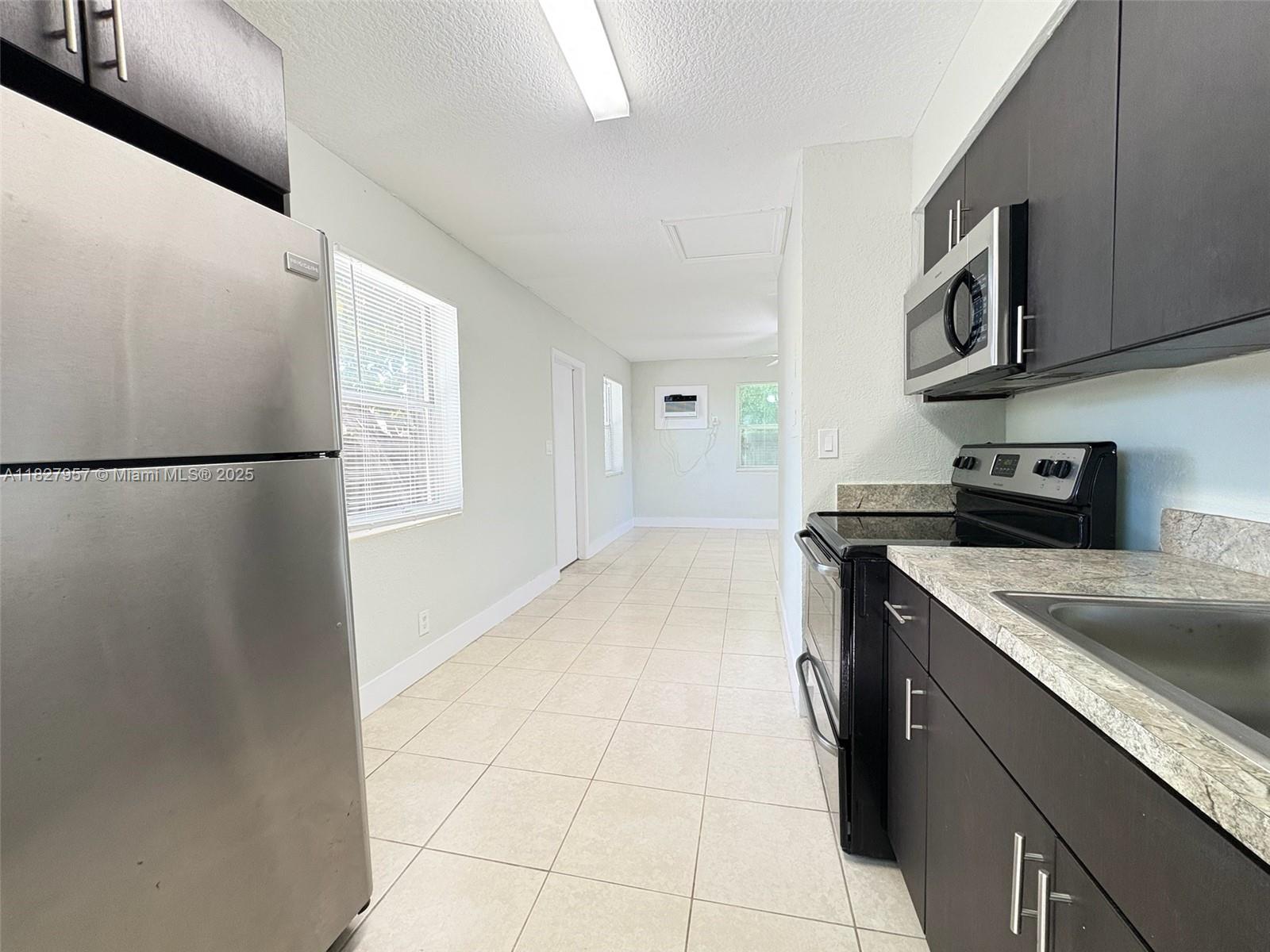 2840 Funston Street, Unit B Hollywood, FL 33020 - Photo 8 of 10 a kitchen with stainless steel appliances granite countertop a refrigerator a stove a sink and a microwave