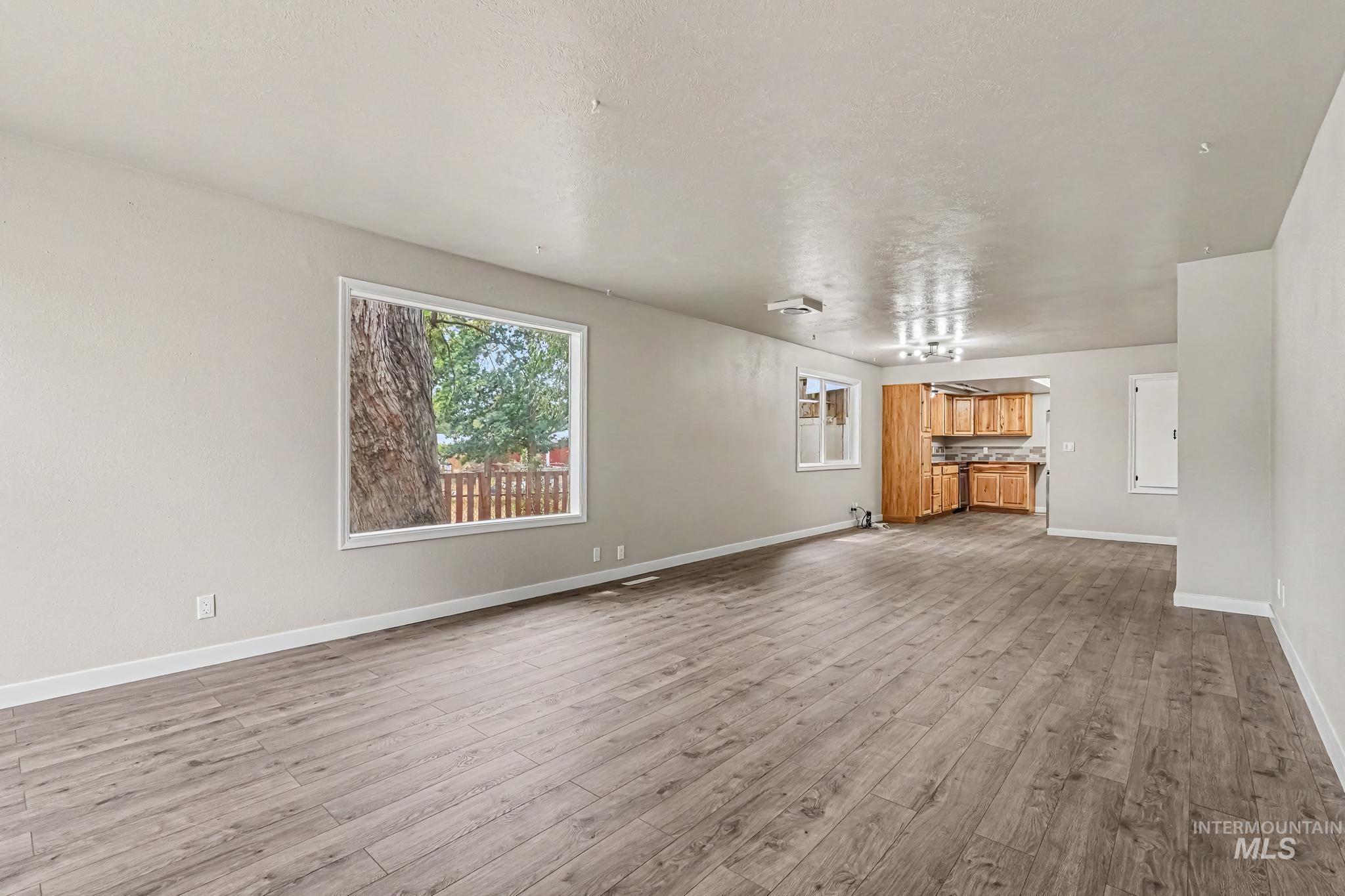 1023 State Street Weiser, ID 83672 - Photo 3 of 25 Spacious open-concept room featuring wood-finish flooring, neutral wall tones, and a large window